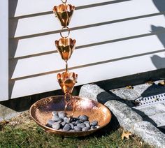 a water fountain with rocks in it on the ground next to a wall and grass