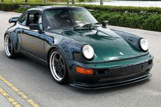 a dark green porsche parked on the side of the road