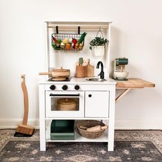 a small white stove top oven sitting next to a wooden shelf filled with pots and pans