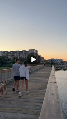 two people and a dog walking on a pier