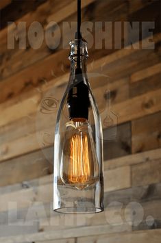 a clear glass light bulb hanging from a ceiling with wood planks in the background