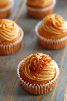 cupcakes with frosting and caramel toppings sitting on a table top