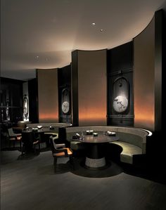 an elegant restaurant with round tables and clocks on the wall behind them, along with benches