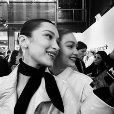 two beautiful women standing next to each other in front of a crowd at an event