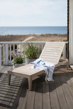 an empty chaise lounge on a deck overlooking the ocean