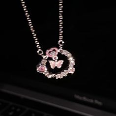 a close up of a laptop with a necklace on it's neck and a butterfly in the middle