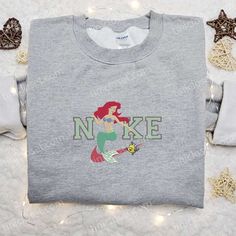 Introducing the Ariel and Flounder x Nike Embroidered Sweatshirt, a magical collaboration between two iconic brands. This sweatshirt showcases stunning embroidery of Ariel and Flounder from The Little Mermaid, bringing your favorite Disney characters to life. With its cozy and comfortable fabric, this sweatshirt is perfect for any occasion. The sweatshirt is not only stylish but also offers excellent durability and quality, ensuring it will be a cherished piece in your wardrobe for years to come Nike Embroidered Sweatshirt, Ariel And Flounder, Maroon Hoodie, Embroidered Shirts, Personal Narratives, Mermaid Disney, Best Gift Ideas, Disney Shirt, Hoodie Material