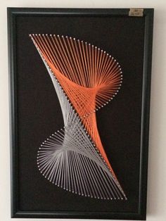 an orange and white art piece hanging on the wall next to a black framed object