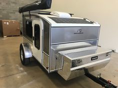 a trailer with a solar panel on the roof and side door is parked in a warehouse