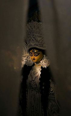 a masked woman standing in the dark with her face painted like a mask and headdress