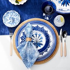 a blue and white table setting with plates, silverware and napkins on it