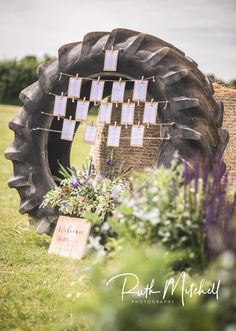 there is a tire that has been decorated with notes on it and flowers in the grass