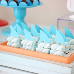 there are many blue and white desserts on the table with cupcakes in the shape of shark fin