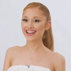 a woman with long hair wearing a white dress and smiling at the camera while standing in front of a white background