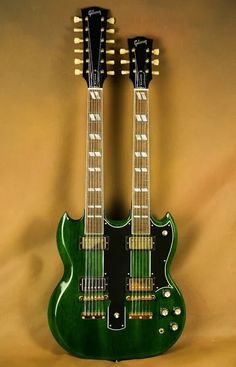 two green guitars sitting side by side on a tan background, one is black and the other is green