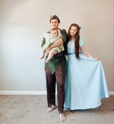 a man and woman dressed up as peter pan with a baby in his arms, standing next to each other