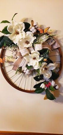 a wooden wheel with flowers in it on the wall next to a clock that says time is 11 00