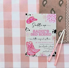 a pink and white checkered table cloth with a notebook, pen and scissors on it