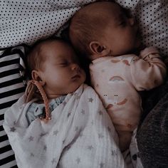 two babies sleeping next to each other on top of a bed with white and black sheets