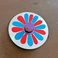 a colorful plate with a cupcake on it sitting on a wooden table next to a bottle opener