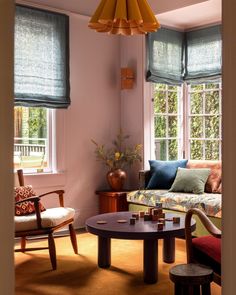 a living room filled with furniture and lots of windows covered in shades on the window sill