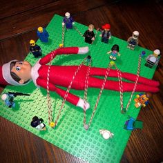 an elf laying on top of a green mat next to legos and other toys