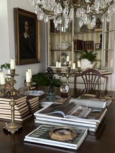 a table topped with lots of books next to a chandelier