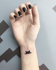 a small black cat tattoo on the wrist