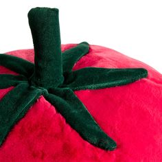 a red and green stuffed animal sitting on top of a white surface