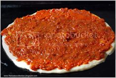 a pizza covered in sauce sitting on top of a black surface