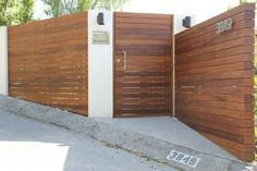 a wooden gate with a sign on the sidewalk