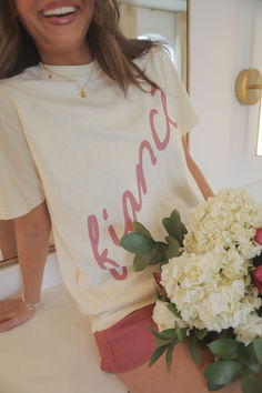 a woman sitting on a bed holding a bouquet of flowers in her hand and smiling