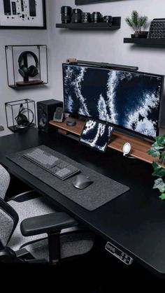 a desk with a computer monitor, keyboard and speakers sitting on top of it next to a potted plant