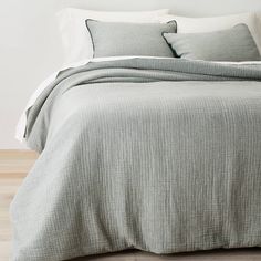 a bed with two pillows on top of it next to a white wall and wooden floor