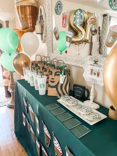 there is a table with starbucks coffee cups on it and balloons in the shape of numbers