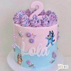 a pink and blue two tiered cake with purple frosting