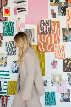 a woman walking past a wall covered in pictures