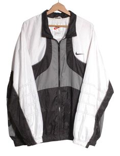 Vintage Nike shell suit jacket from the late 1990's. Retro design in a white, black and grey colour. Nike swoosh on the chest and back. Zip front and twin waist pockets. Elasticated waist and cuffs. Made in Malaysia from a nylon fabric. Label reads XXL. Condition: Excellent vintage condition. Chest: 48in Length: 29in Inside sleeve: 21in More vintage clothing on our website www.brickvintage.com Vintage White Track Jacket, Retro White Track Jacket For Streetwear, Vintage White Track Jacket For Streetwear, 90s White Sports Outerwear, Vintage White Long Sleeve Track Jacket, White 90s Track Jacket For Winter, White 90s Style Track Jacket For Winter, 90s Style White Track Jacket For Winter, 90s White Track Jacket For Winter