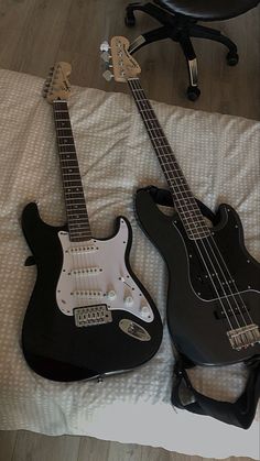 two electric guitars are laying on a bed