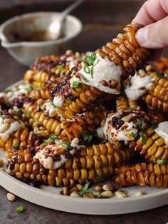 someone is dipping some kind of food on top of corn