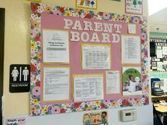 a bulletin board with flowers on it in a school cafeteria area, surrounded by tables and chairs