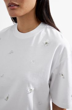 Sparkly, embellished flower appliqués add textural elegance to this boxy T-shirt made from soft cotton. 26" length Crewneck Short sleeves 100% cotton Dry clean or machine wash, dry flat Made in Turkey White Crew Neck T-shirt With Floral Applique, White Embellished Crew Neck Top, White Embellished Crew Neck T-shirt, Oversized Floral Embroidery Crew Neck Top, Oversized Floral Embroidered Crew Neck Top, White Short Sleeve T-shirt With Floral Applique, Casual Embellished Crew Neck T-shirt, Spring Embellished Cotton T-shirt, White Crew Neck Top With Floral Applique