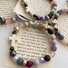 two bracelets with cross charms on them sitting next to an open book