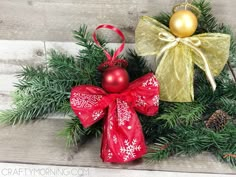 two christmas decorations on top of evergreen branches with red bows and gold ornament