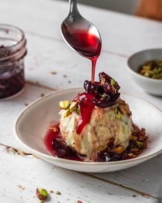 a spoon drizzling sauce onto a dessert on a plate