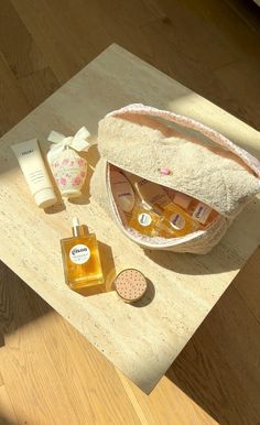 an open bag sitting on top of a wooden table next to bottles and soaps