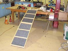 a workbench in a garage with tools on the table and stairs up to it