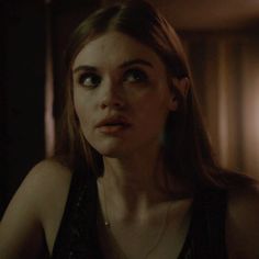 a woman in a dark room looking at the camera with an evil look on her face