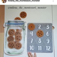 a child's hand next to a mason jar with buttons and numbers on it