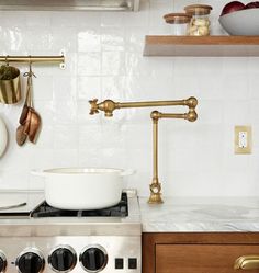 a stove top oven sitting next to a wall mounted pot rack with pots and pans on it